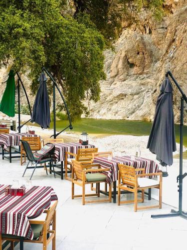 a group of tables and chairs with umbrellas at Wadi Al Arbeieen Resort in Muscat