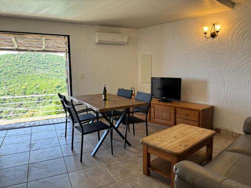 un salon avec une table, des chaises et une télévision dans l'établissement CAROLE F3, à Sainte-Lucie de Porto-Vecchio