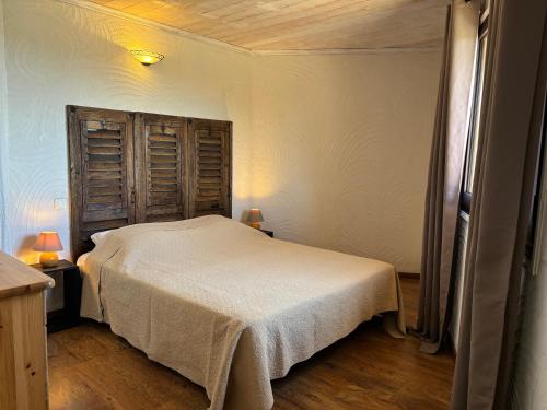 Un dormitorio con una cama blanca y un cabecero de madera. en CAROLE F3, en Sainte-Lucie de Porto-Vecchio