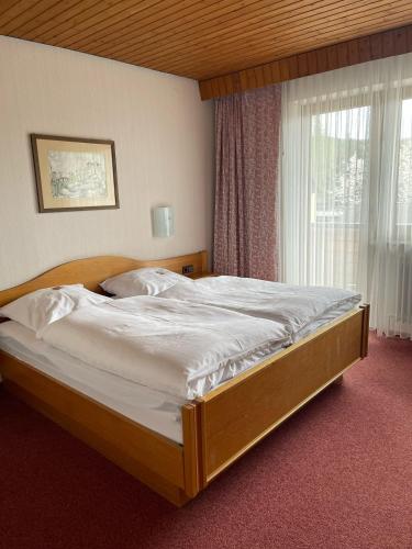 a large bed in a bedroom with a window at Landhotel Jägerhof in Bischofsgrün