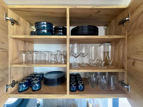 a wooden cabinet filled with glasses and dishes at Houseboat 11 direct aan het Sneekermeer in Offingawier
