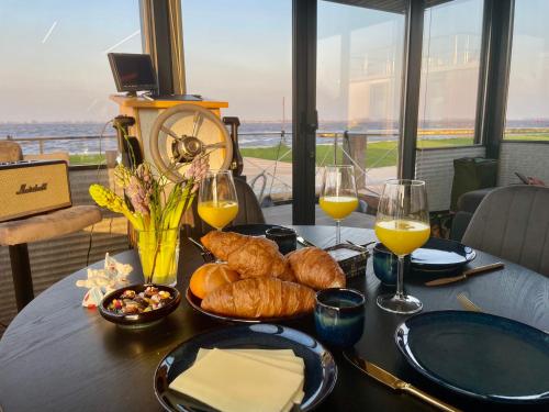 a table with a plate of bread and glasses of wine at Houseboat 11 direct aan het Sneekermeer in Offingawier