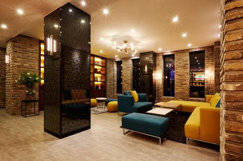 a lobby with yellow and blue chairs and tables at Urban Island Hotel Jeju in Jeju