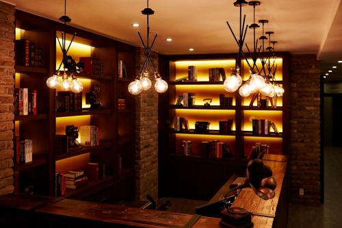 a room with a library with bookshelves and lights at Urban Island Hotel Jeju in Jeju