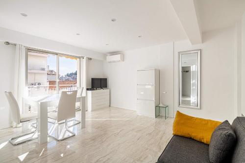 un salon blanc avec une table et un canapé dans l'établissement LE LOUIS BLANC avec balcon en plein centre-ville, à Cannes