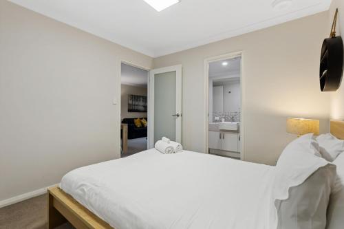 a bedroom with a white bed and a bathroom at Yaran Suites in Rockingham