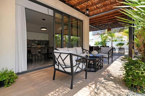 an outdoor patio with chairs and a table at Villa Evergreen - 3bed Bungalow large pool in Protaras