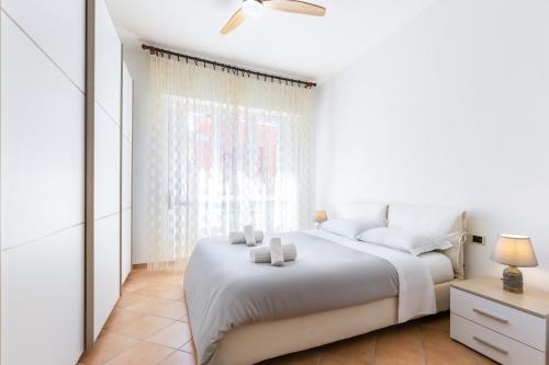 a white bedroom with a white bed and a window at Hostdomus-Casa Marais in Finale Ligure
