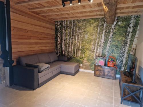 a couch in a room with trees on the wall at Gîte des Catalpas in Vollore-Ville