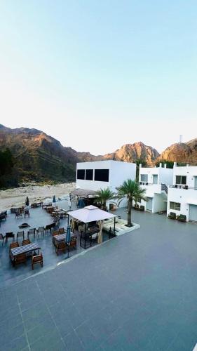 a large patio with tables and benches and buildings at Wadi Al Arbeieen Resort in Muscat