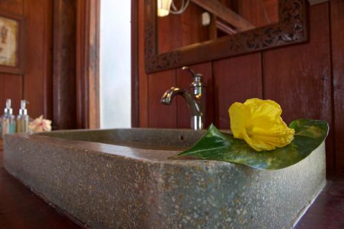 a yellow flower sitting on top of a bathroom sink at Terres Rouges Lodge in Banlung
