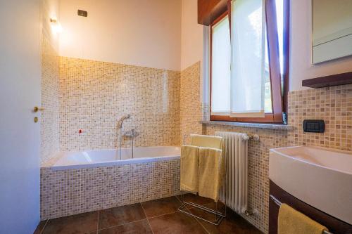a bathroom with a tub and a sink and a window at Villa Mavica in  Monvalle 
