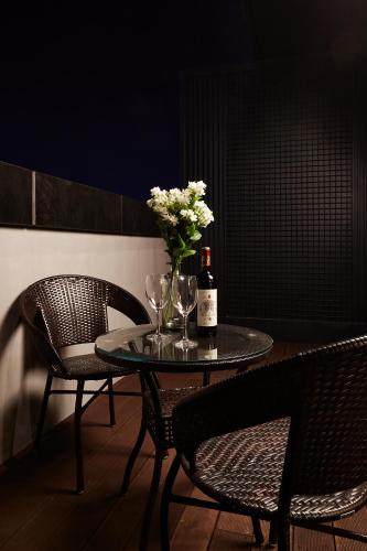 a table with two chairs and a bottle of wine and flowers at Urban Island Hotel Jeju in Jeju