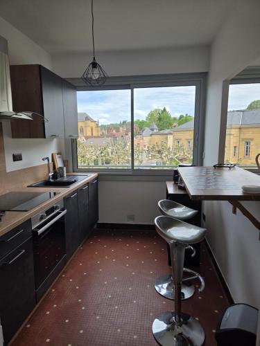 une cuisine avec deux tabourets et une grande fenêtre dans l'établissement le cocon sarladais, appartement centre ville avec balcon et parking privé, à Sarlat-la-Canéda