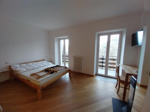 a living room with a bed and a desk and windows at La Casa nel Bosco BeB in Bee