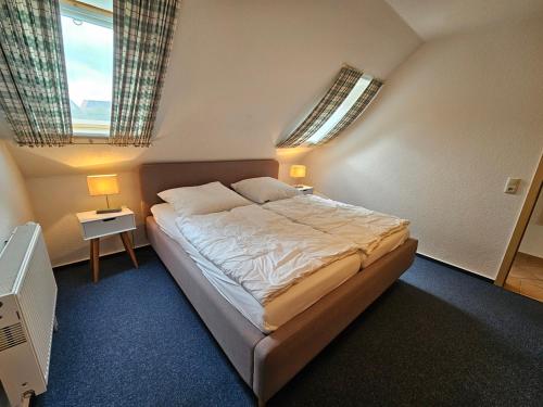 a bedroom with a large bed and two windows at Pferdekoppel im Haus zwischen den Wassern in Behrensdorf