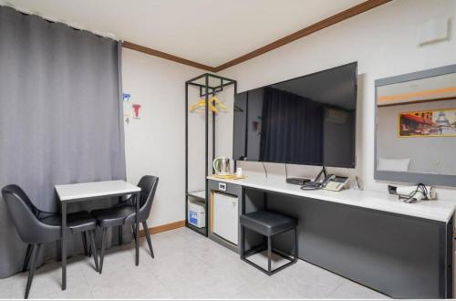 a room with a desk and a table and chairs at Donghae Gloria Hotel in Donghae
