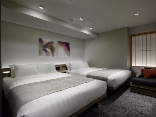 a hotel room with two beds and a couch at Premium Apart MONday GINZA EAST in Tokyo