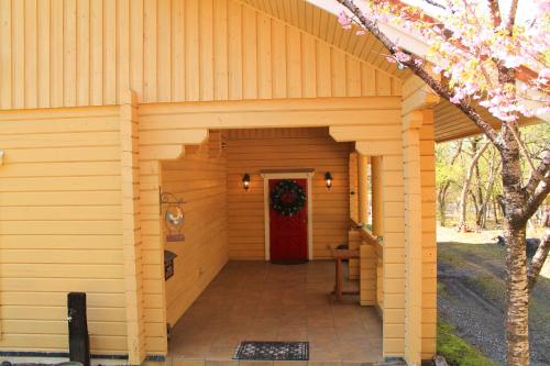 a large wooden building with a red door at 彩の宿虹 in Yamanakako