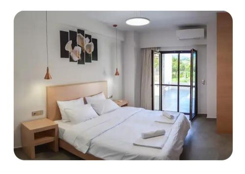 a bedroom with a large white bed and a window at Kamilos apartments in Monastirákion