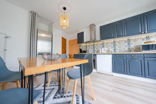 une cuisine avec des placards bleus et une table et des chaises en bois dans l'établissement Appartement 4 chambres - CAEN, à Caen