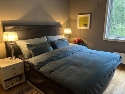 a bedroom with a bed with a blue comforter and two lamps at Leilighet Rjukan sentrum in Rjukan