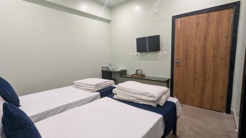 two beds in a room with a door and a tv at MAHA RAAS A unit of RAAS LEELA Hotels and Resort in Udaipur