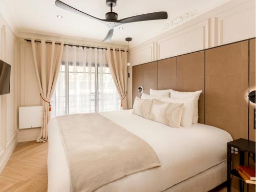 une chambre avec un grand lit blanc et une fenêtre dans l'établissement Merveil - Luxury Suite -Marais - Bvd Saint Denis, à Paris