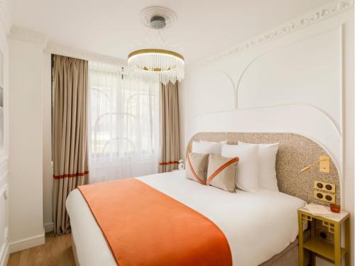 une chambre avec un grand lit blanc avec une couverture orange dans l'établissement Merveil - Luxury Suite - Marais - Lenoir II, à Paris