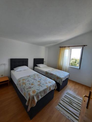 two beds in a room with a window at Apartman Val in Rogoznica