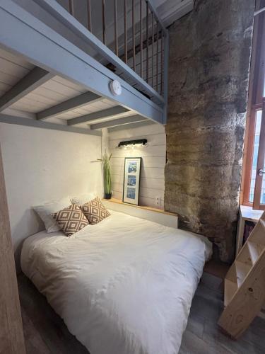 Cette chambre comprend un grand lit blanc et un mur en briques. dans l'établissement Atypique & cosy Hyper-centre Lyon et Quais, à Lyon
