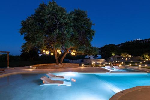 a swimming pool at night with white lounge chairs at Hamilton Grand Villa in Koskinou