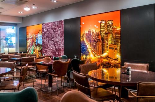a restaurant with tables and chairs and a large painting on the wall at Scandic Stora Hotellet in Nyköping