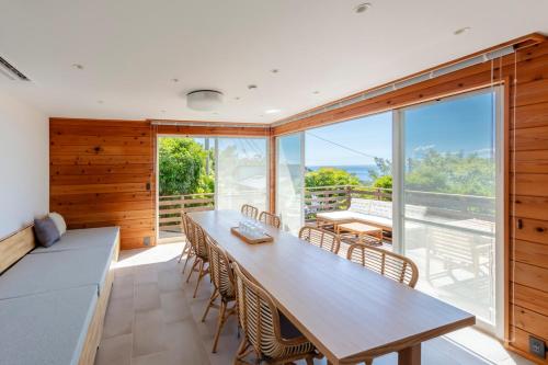 伊東市にあるVilla ORBのテーブルと椅子と大きな窓のあるダイニングルーム