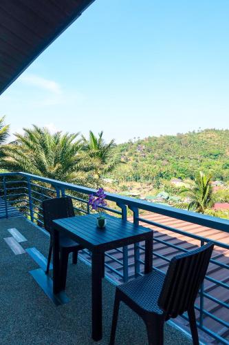 a table and chairs on a balcony with palm trees at AV Suites in Puerto Galera