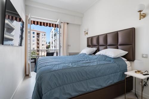 une chambre avec un lit avec une couette bleue et une fenêtre dans l'établissement Rose des Sables - 4min à pied de la Plage, à Antibes