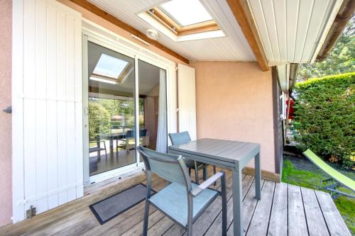 - une table et des chaises sur une terrasse couverte avec une fenêtre dans l'établissement Chalet dans résidence piétonne, à Hourtin