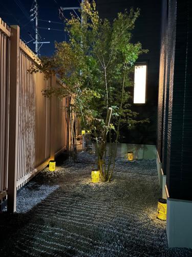a fence with a tree in a yard at night at 梅の由 離れUMENOYU-HANARE 120m2 in Dazaifu