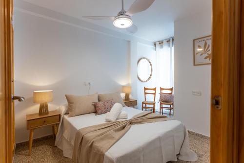 a white bedroom with a bed and two chairs at Comeback LOOKING FOR THE SUMMER in Motril