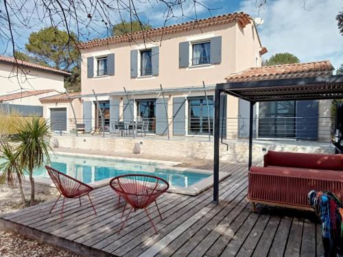 une maison avec une piscine et deux chaises sur une terrasse dans l'établissement La villa du Pont du Gard, à Castillon-du-Gard