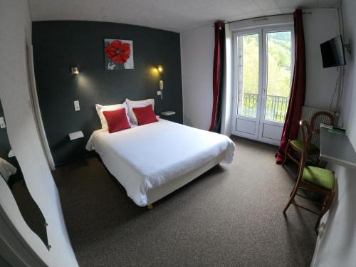 a bedroom with a large white bed and a window at Hôtel de Londres in Le Mont-Dore