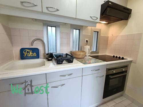 une cuisine avec des armoires blanches et un évier dans l'établissement Appartement résidence calme avec balcon, à La Rochelle