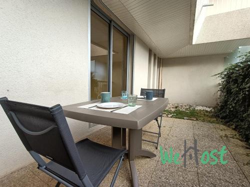 une table et une chaise assises sur une terrasse dans l'établissement Appartement résidence calme avec balcon, à La Rochelle
