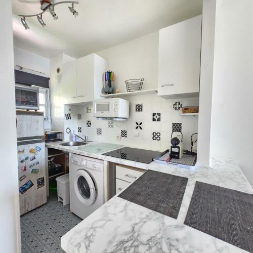une cuisine blanche avec une machine à laver à l'intérieur dans l'établissement Appartement à deux pas de la mer, à Saint-Laurent-du-Var