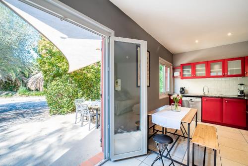une cuisine et une salle à manger avec des armoires rouges et une table dans l'établissement Le Paradis - maison avec jacuzzi, à Argelès-sur-Mer