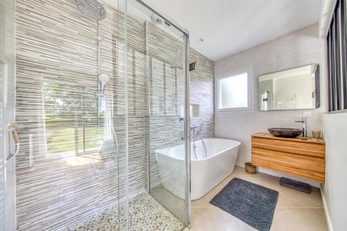 une salle de bain avec baignoire et douche en verre dans l'établissement Villa Atlantica - Grayan, Médoc, à Grayan-et-lʼHôpital