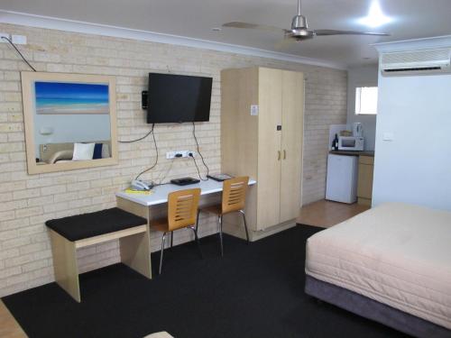 a hotel room with a desk and a bed and a bedroom at Aston Hill Motor Lodge in Port Macquarie