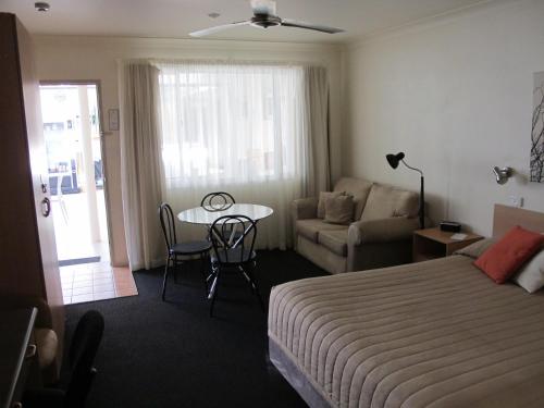 a hotel room with a bed and a table and a couch at Aston Hill Motor Lodge in Port Macquarie