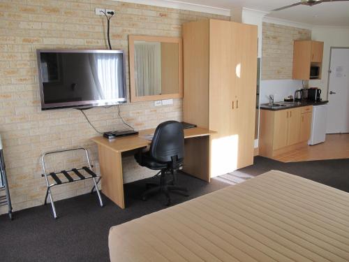 a room with a desk and a chair and a television at Aston Hill Motor Lodge in Port Macquarie
