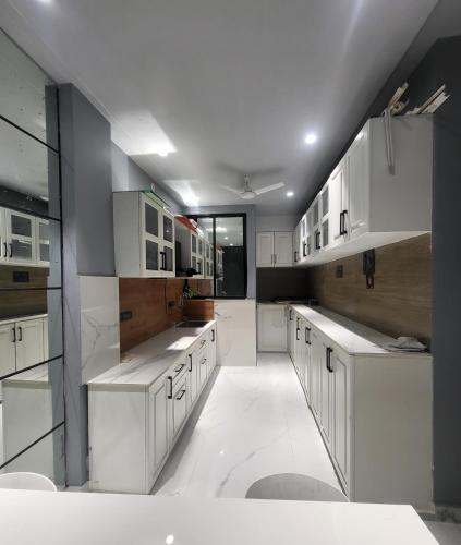 a large white kitchen with white counters and cabinets at The Glass Home in Prayagraj